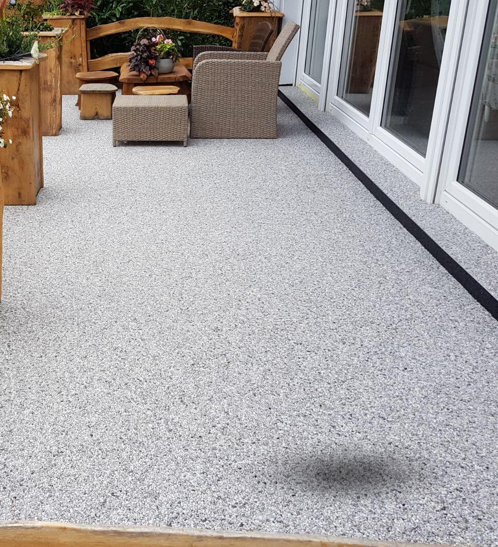 taras wykonanay w kamiennym dywanie w kolorze bardigilio z meblami ogrodowymi w tle